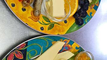 A colorful plate with scrambled eggs, ham, cheese, and various fruits and vegetables.