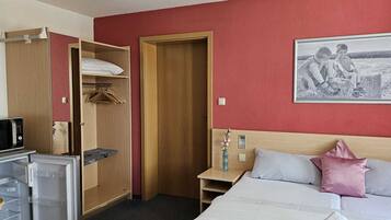 Ein Hotelzimmer mit Bett, Fernseher, Schrank und einem Bild an der Wand.