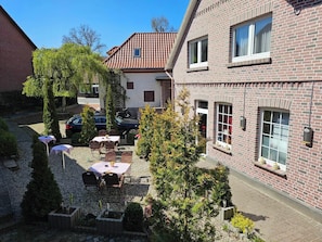 Ein Innenhof mit Außenbestuhlung, einem Auto und einem Backsteinhaus mit Fenstern.