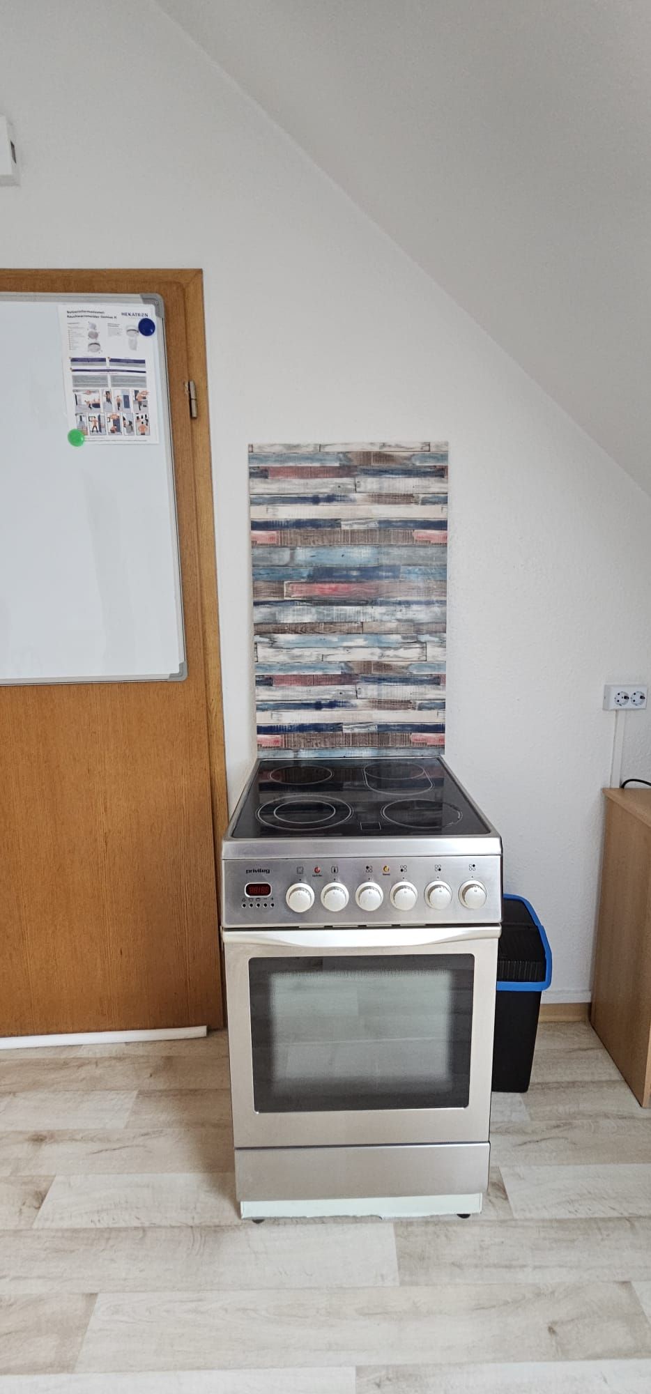 Eine Küche mit integriertem Herd und Backofen, einer Tafel mit Notizen und einer Holztür.