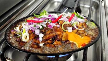 A hot pot meal with various ingredients and garnishes on a stove.