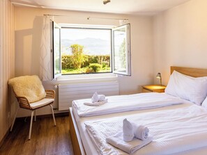 Une chambre d’hôtel avec un lit, une chaise, une fenêtre donnant sur un paysage agréable et une table de chevet.
