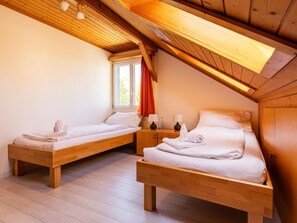 A room with two wooden beds, a window with curtains, and a wooden ceiling. - Hauswurz Appartement/Fewo Appartement/Fewo by Interhome (Gwatt (Thun))