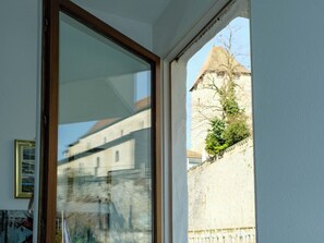 Ein Zimmer mit großem Fenster mit Blick auf ein historisches Gebäude und einen Baum.
