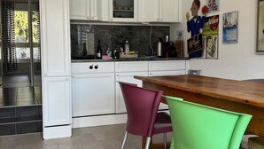 Uma cozinha moderna com armários brancos, bancada de madeira e duas cadeiras.