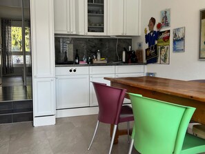 Eine moderne Küche mit weißen Schränken, einer Holz Arbeitsplatte und zwei Stühlen.