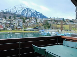 Blick von einem Balkon auf einen See mit Booten, im Hintergrund ein Berg und eine Stadt mit Häusern und Gebäuden.