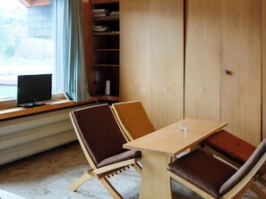 A room with a wooden table and chairs, a television on a windowsill, and a bookshelf. - Seewohnung 1 Appartement/Fewo, Dusche Appartement/Fewo, Dusche by Interhome (Spiez)