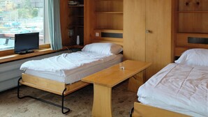 Ein Zimmer mit zwei Betten, einem Schreibtisch und einem Fernseher.
