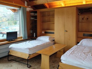 Ein Zimmer mit zwei Betten, einem Schreibtisch und einem Fernseher.