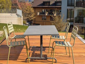 A patio with a table and chairs, surrounded by a wooden deck and a view of residential buildings. - Ambiente Appartement/Fewo Appartement/Fewo by Interhome (Spiez)
