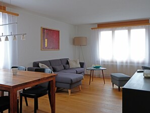 Ein modernes Wohnzimmer mit einer Couch, einem Esstisch und einer Lampe.