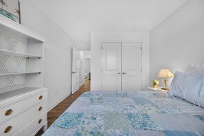 Une chambre à coucher avec un lit, une table de chevet, une lampe, une commode et une porte.