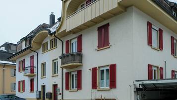 Un immeuble à plusieurs étages avec des volets rouges, un balcon et un garage.