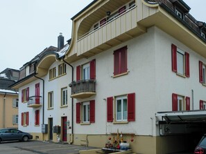 Ein mehrstöckiges Gebäude mit roten Fensterläden, einem Balkon und einer Garage.