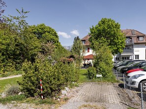 Ein Wohngebiet mit befestigter Auffahrt, geparkten Autos und einem Schild mit der Aufschrift 'FEWO'.