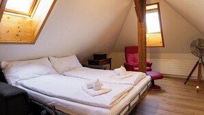 Un dormitorio con una cama, una silla roja, un ventilador y una estructura de techo de madera.