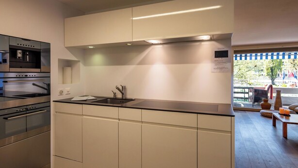 A modern kitchen with built-in appliances, a large island, and a view of the outdoors. - Buchtoase Appartement/Fewo 4-Bett Wohnung by Interhome (Spiez)