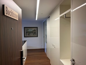 Ein Flur mit einer Holztür mit der Aufschrift 'Buchthaus', einem gerahmten Bild an der Wand und einer Glastür auf der rechten Seite.