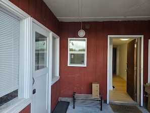 A red exterior wall with a white door, a window, and a doorbell. - Studio Near Airport & City - Cozy Green Retreat! (Seattle)