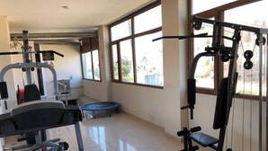 A gym with various exercise equipment, a trampoline, and large windows allowing natural light. - YUMURTALIK OTEL (Yumurtalık)