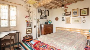 Ein Zimmer mit einem Bett, einem Schreibtisch und einem Sessel. An den Wänden hängen Bilder und auf der Kommode steht ein Globus.