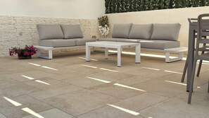 Un salon moderne avec deux canapés gris, une table basse blanche et un fauteuil gris.
