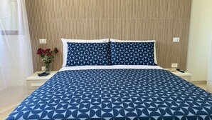 Ein Hotelzimmer mit einem Bett, einem Nachttisch, einer Vase mit Blumen und einer Wand mit vertikalen Linien.
