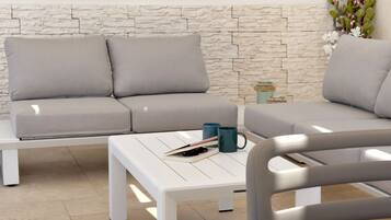 A modern living room with a stone-textured wall, a grey sofa, a white coffee table, and a blue mug.