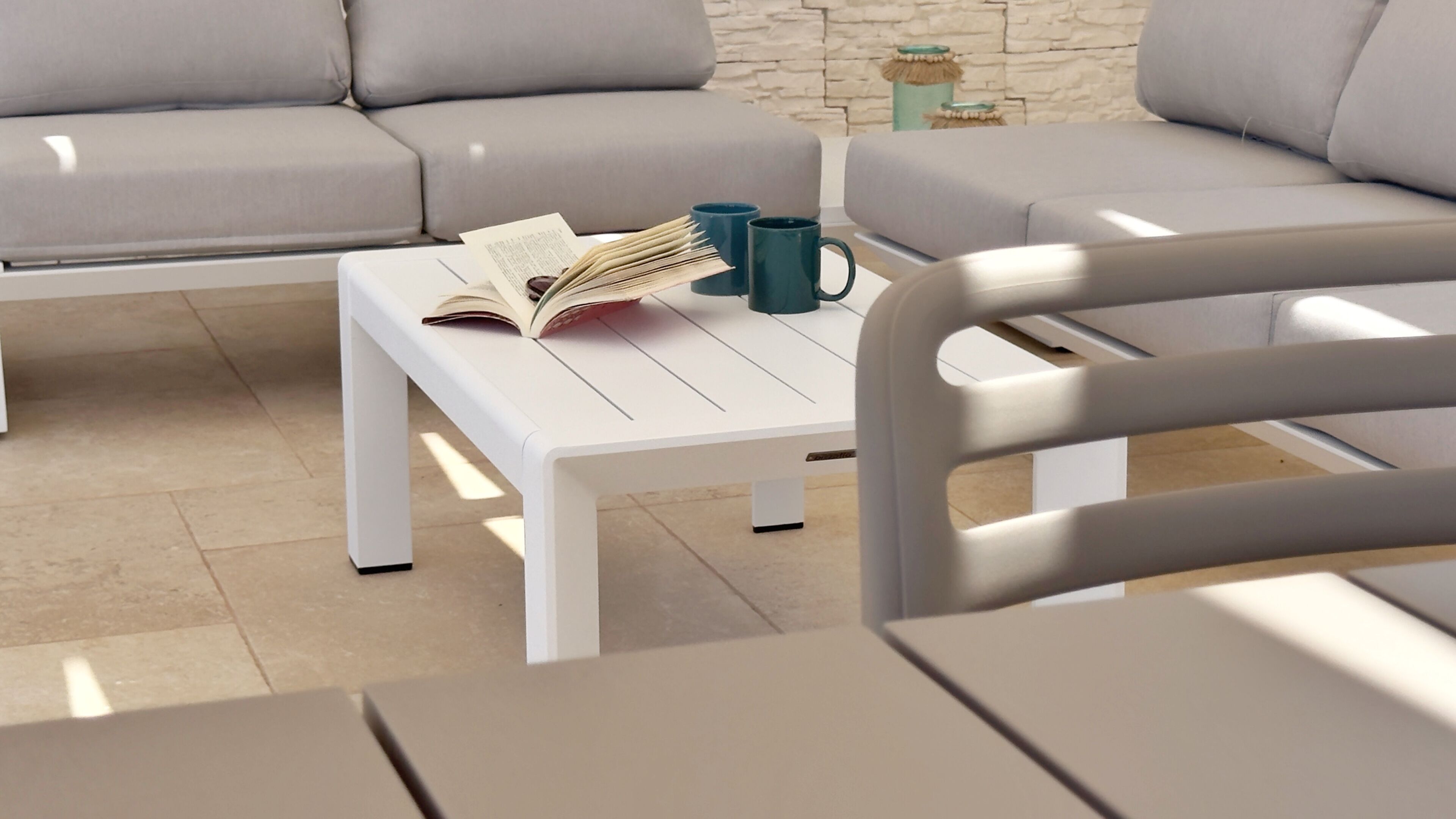 A modern living room with a white coffee table, a book, and two mugs.