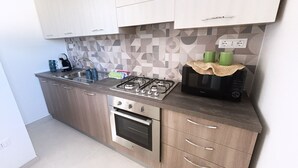 Eine moderne Küche mit Gasherd, Backofen, Mikrowelle und Kaffeemaschine.