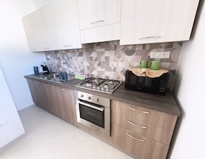A modern kitchen with a gas stove, oven, microwave, and a coffee maker. - Alisìa (San Pietro In Bevagna)