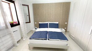 A hotel room with a bed, bedside tables, a mirror, and a window with curtains. - Alisìa (San Pietro In Bevagna)