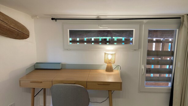 A study room with a desk, chair, lamp, window, and blinds.
