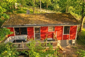 Een rode woning met veranda, schoorsteen en houten omheining.