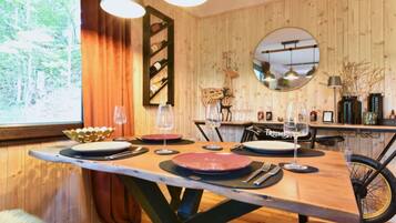 A wooden dining table with plates and glasses, a mirror, and a bicycle in the background.