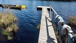 Un moll de fusta que s'allarga cap a un llac, amb una piragua i una canoa amarrades a prop.