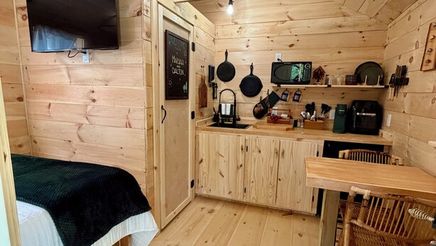Un interior de fusta amb llit, televisió, zona de cuina amb fogó i rentapeus.