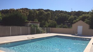 A rectangular swimming pool with clear blue water, surrounded by a tiled deck and a metal fence. - Mobile home near the ocean with a pool (Le Pradet)