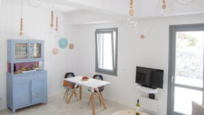 Zona d'estar àmplia amb taula de dinar, cadirees, sofà, televisió i un armari.
