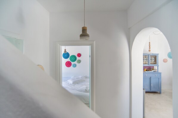 Ein Zimmer mit einem Bett, einer Tür zu einem anderen Raum und einer hängenden Leuchte.