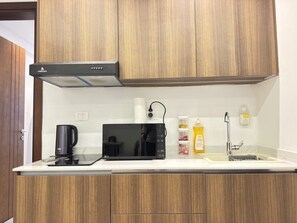 A kitchen with a microwave, coffee maker, and a sink.