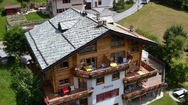 A multi-story hotel with balconies, outdoor seating, and a garden area. - Adora Leukerbad # 4-bed apartment, Bad, WC by Interhome (Leukerbad)