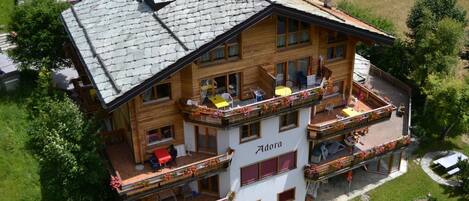 Un hôtel à plusieurs étages doté de balcons, d’un espace extérieur aménagé pour s’asseoir et d’un jardin.