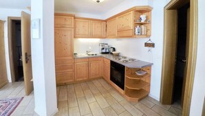 A compact kitchen with wooden cabinets, a built-in oven, and a countertop with a coffee maker. - Adora Leukerbad # 4-bed apartment, Bad, WC by Interhome (Leukerbad)