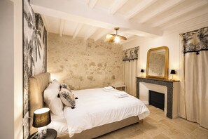 Ein Schlafzimmer mit einem Bett, einem Kamin, einem Spiegel und einer Wand mit einem Blumenmuster.