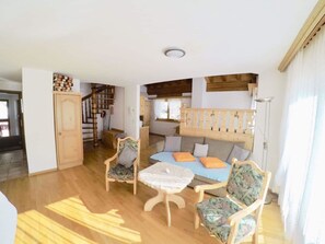 A spacious living room with a wooden staircase, a sofa set, and a dining table. - Adora Leukerbad # 6-bed apartment, Bad, WC by Interhome (Leukerbad)