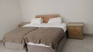 A double bed with a wooden headboard, two bedside tables, and a bench at the foot of the bed.