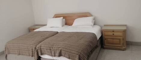 A double bed with a wooden headboard, two bedside tables, and a bench at the foot of the bed.
