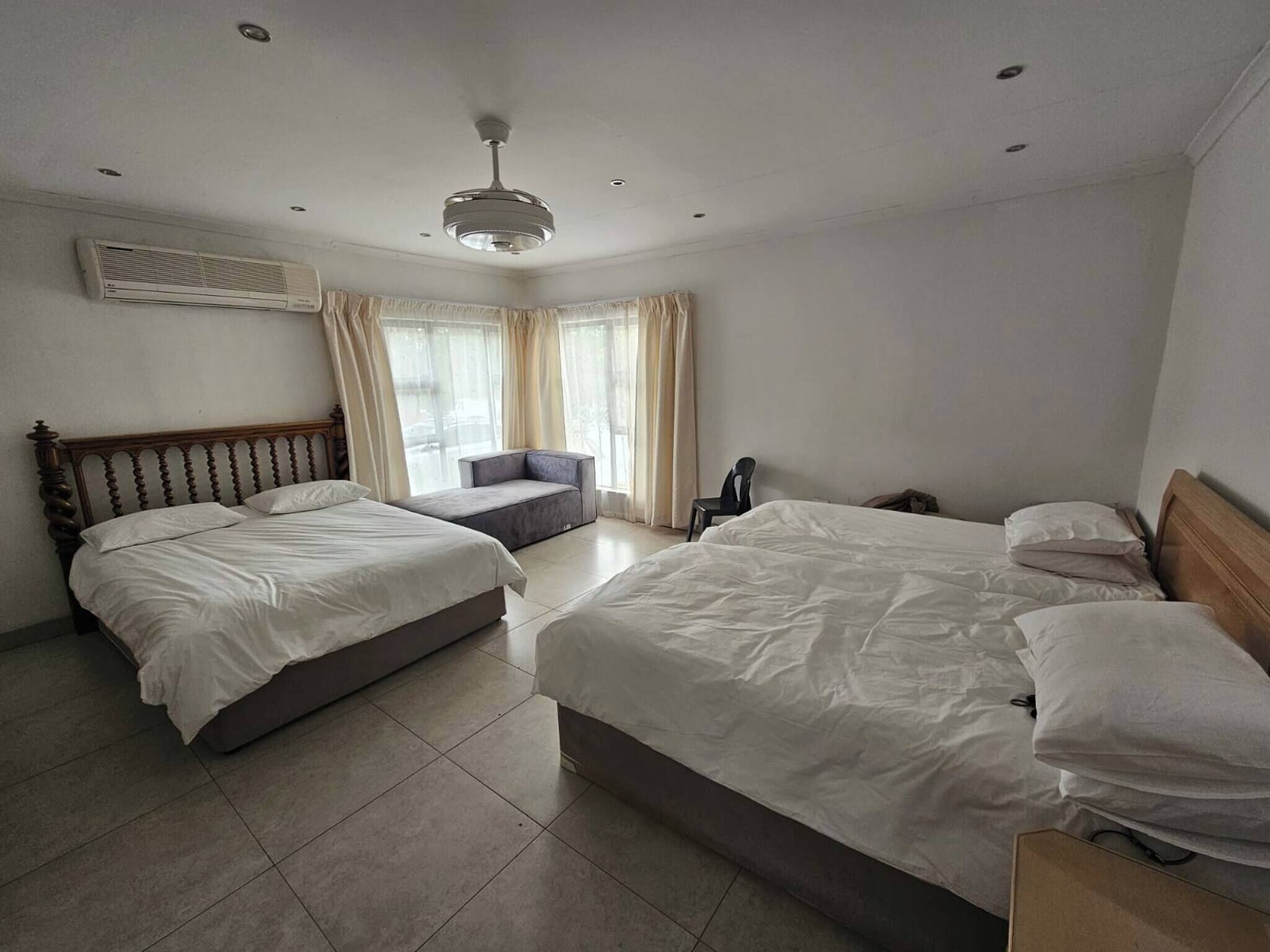 Habitación de hotel con dos camas, un sofá, una silla y un ventilador de techo.